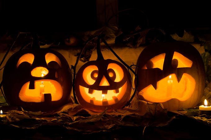 Photo composition from three pumpkins on Halloween. Crying, mad and afraid of some pumpkin against an old window, leaves and candles.