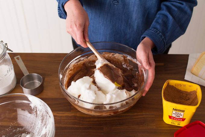 Person using a spatula to fold together chocolate and cream