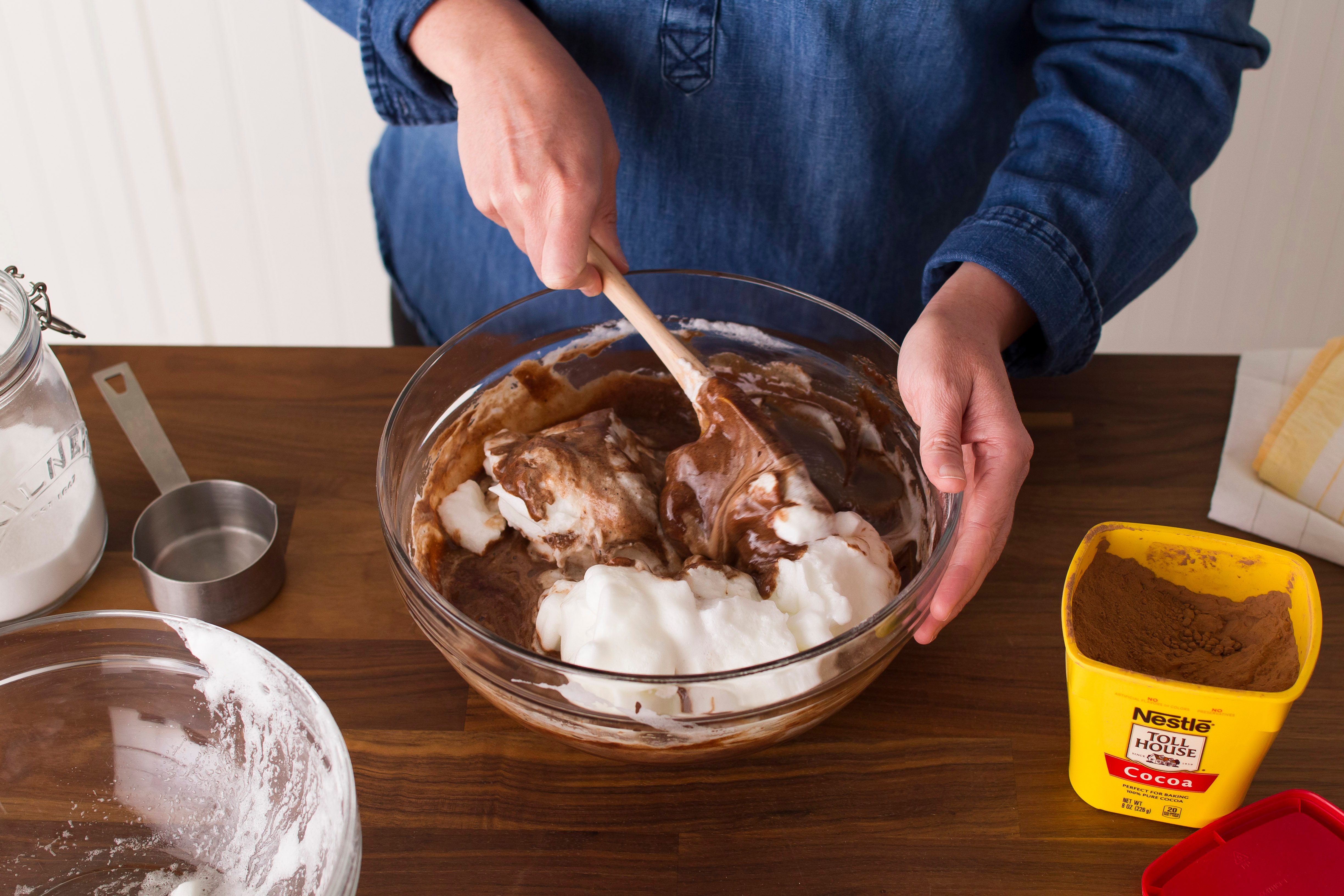 Person using a spatula to fold together chocolate and cream and rotating as they go