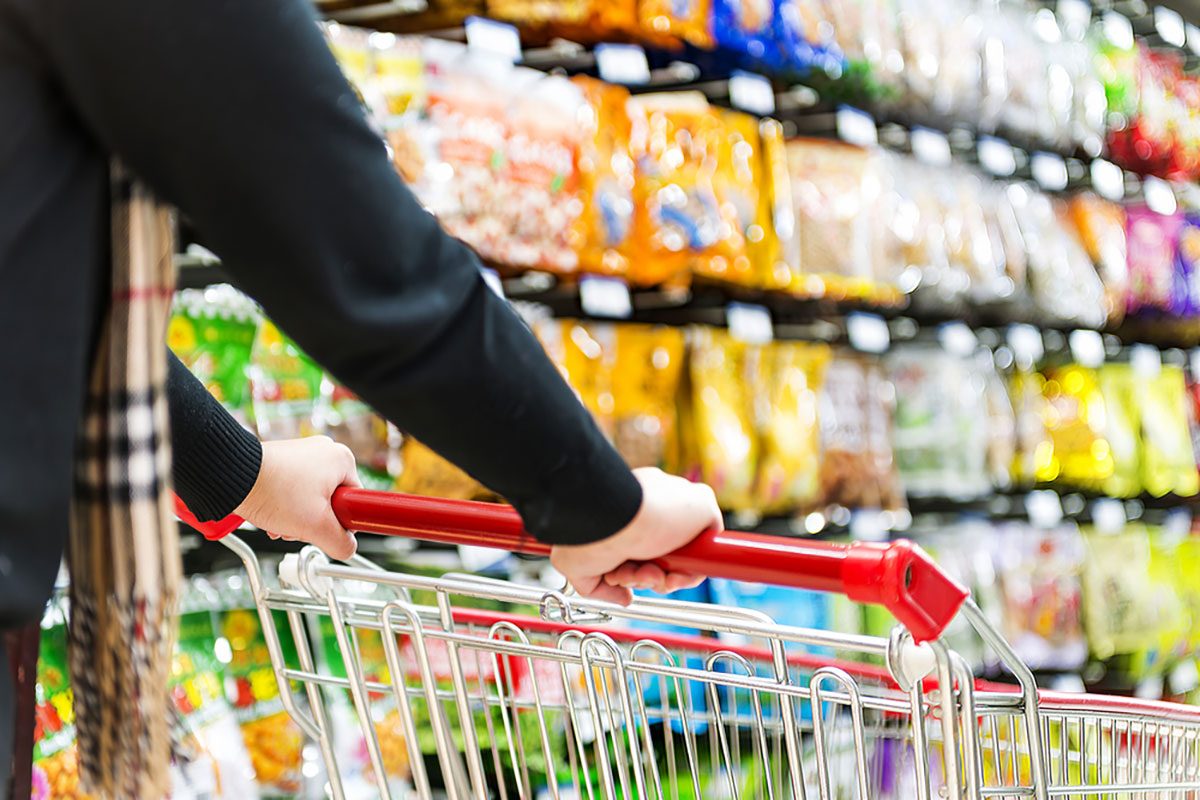 Lady pushing a shopping cart in the supermarket.