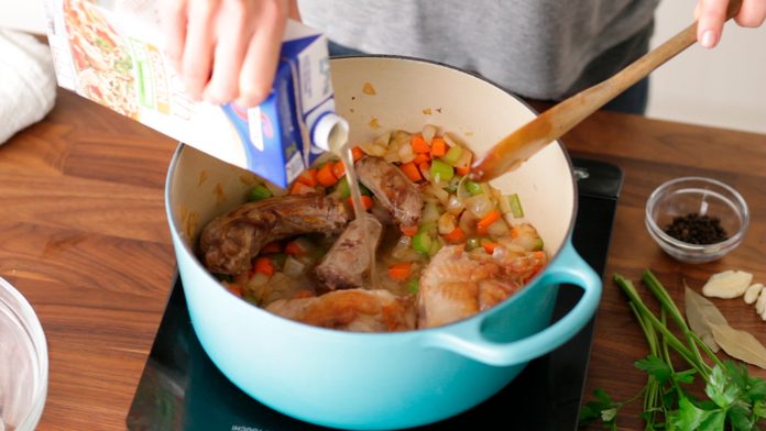 Chicken stock being added to the turkey bone and diced vegetables