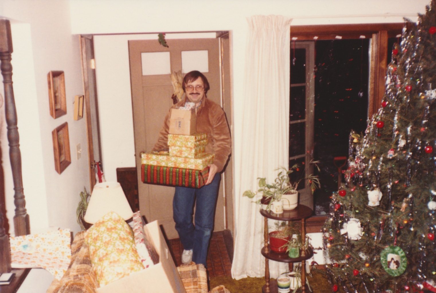 Man coming in through the front door with a present in hand