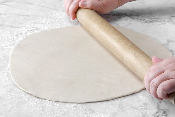 A person rolling out dough with a rolling pin