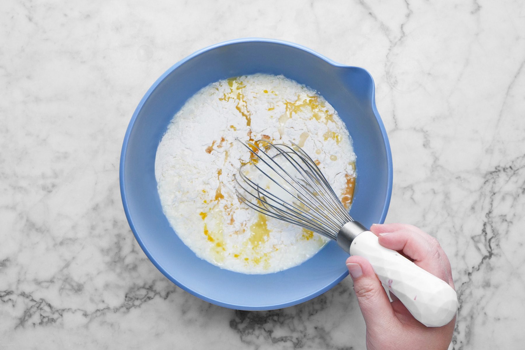 A person stirring the mixture in a large bowl