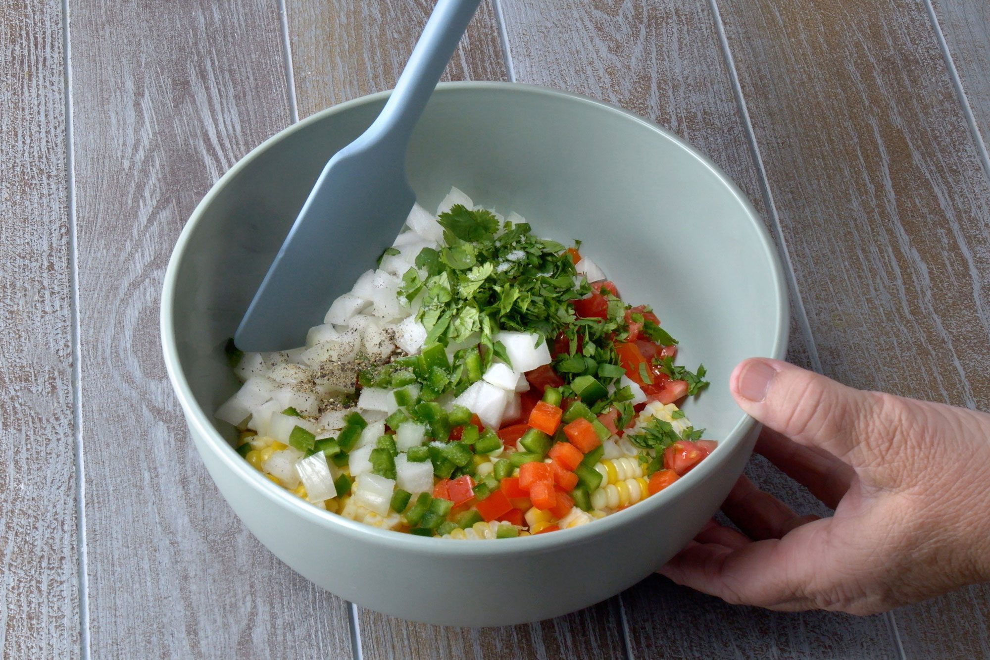 Added tomatoes, onion, cilantro, lime juice, peppers, salt and pepper stirring with spatula in a bowl