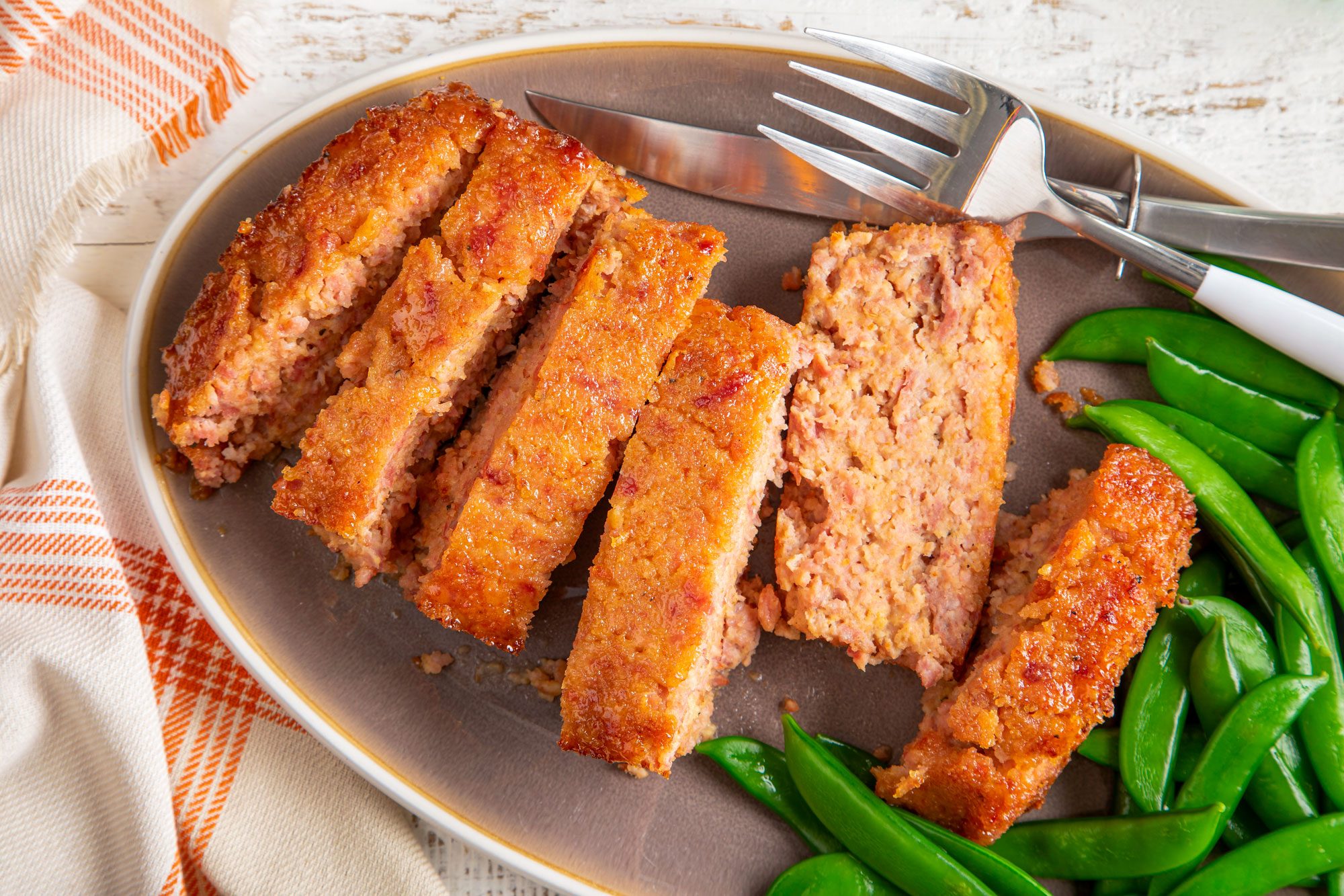 Ham Loaf Served in a Plate with Fork and Knife on Wooden White Painted Surface