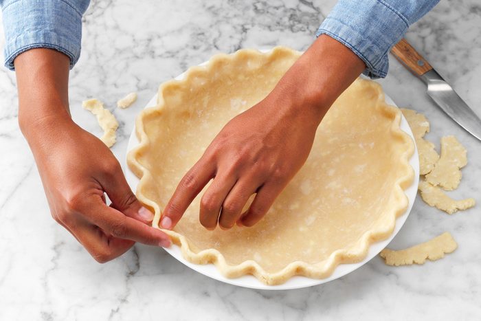 A Person's Hands Touching a Pie Crust
