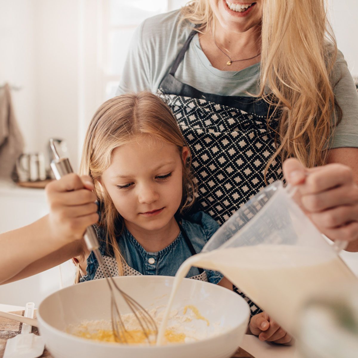 Cute little girl and her mother mixing batter in the bowl. Mother pouring milk with daughter whisking the batter.; Shutterstock ID 547492798; Job (TFH, TOH, RD, BNB, CWM, CM): Taste of Home
