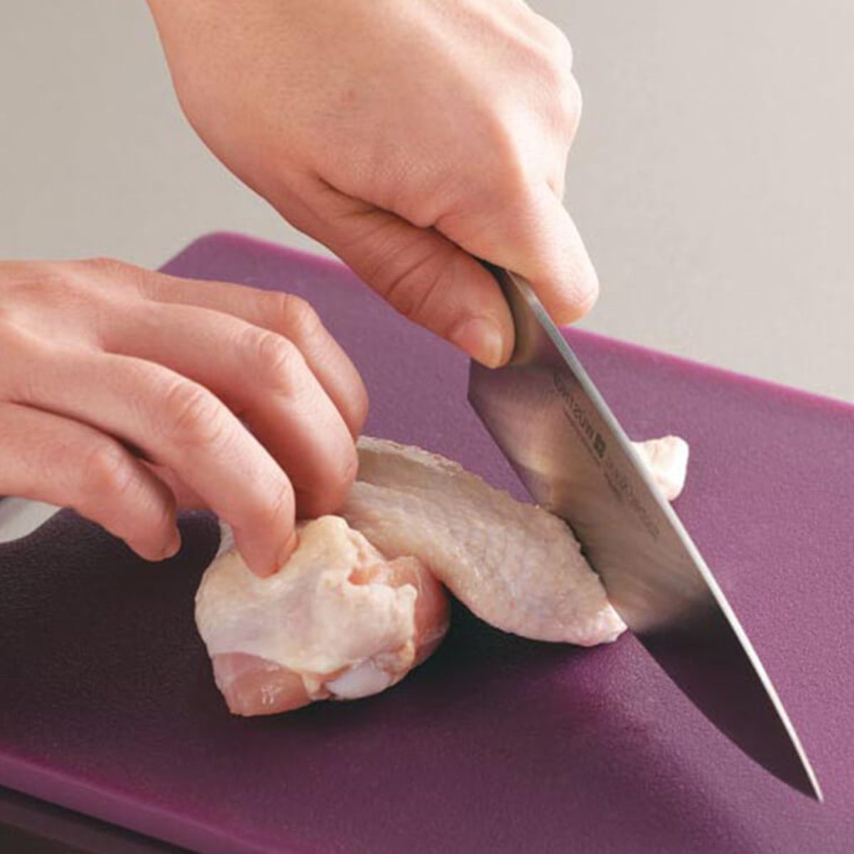 Person cutting the tip off their chicken wing