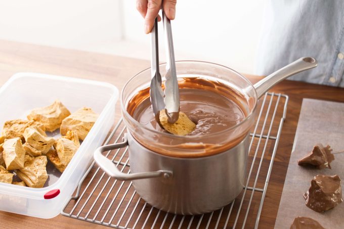 dipping sponge candy into a melted chocolate