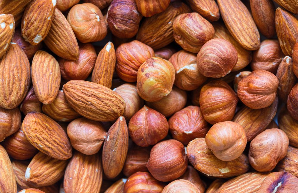Nuts pile background. Cashew, almond, hazelnut mix closeup. Organic food rustic banner template. Tasty healthy snack. Scattered nut on table top view. Nut assortment flat lay. Nut texture. Nut package;