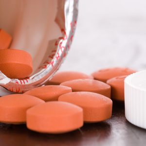 Over the counter medication on black table with bottle and cap