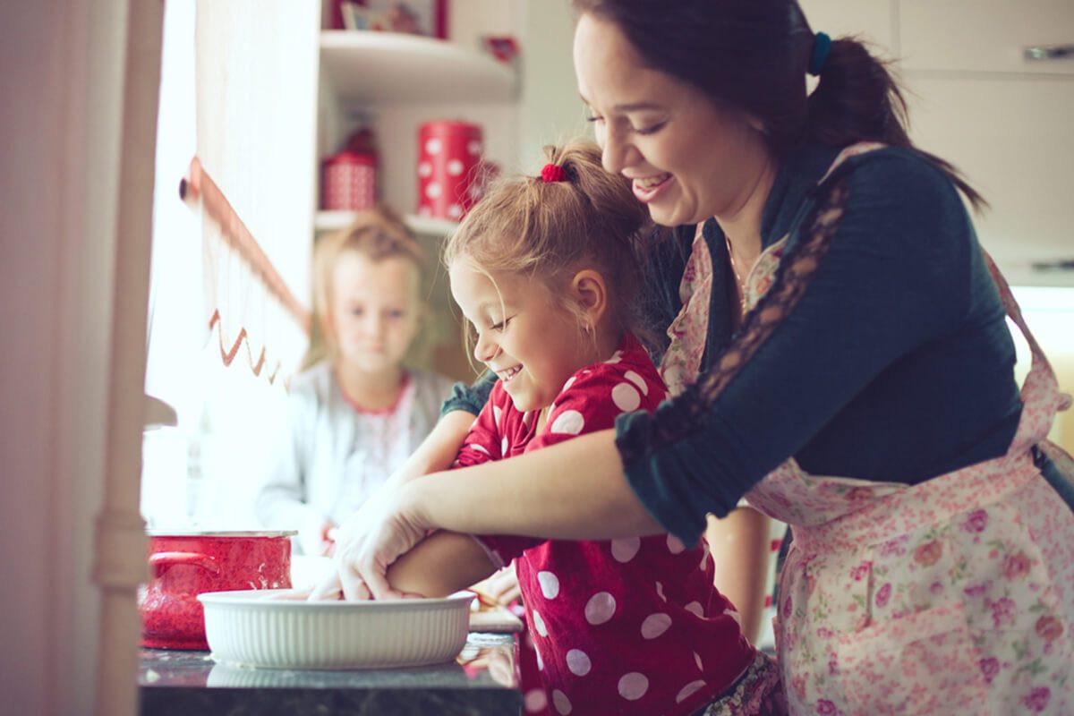Mother with her 5 years old kids cooking holiday pie in the kitchen to Mothers day
