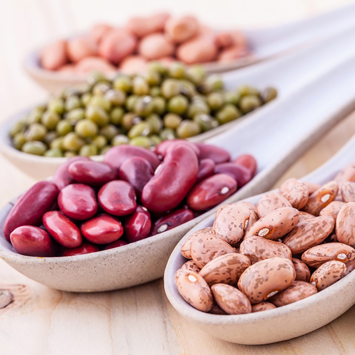 Assortment of beans and lentils in wooden spoon on wooden background. mung bean, groundnut, soybean, red kidney bean , black bean ,red bean and brown pinto beans