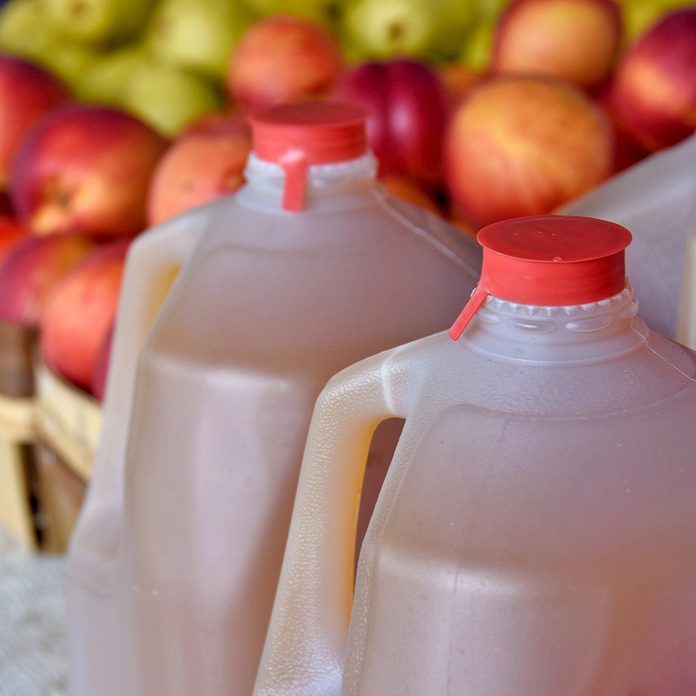 apple cider in plastic jugs with apples in produce boxes at the farmers market