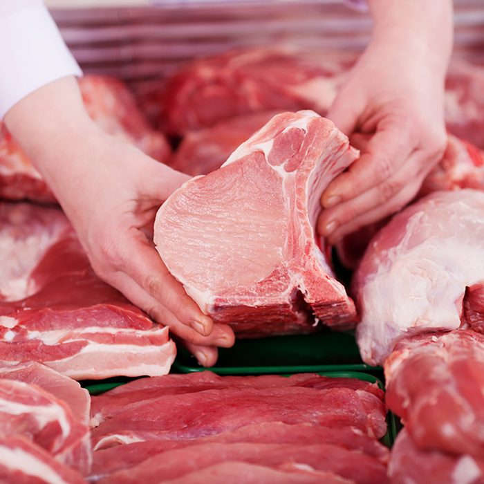 Closeup of butcher's hands holding meat piece in shop