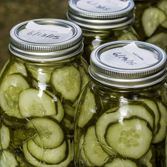 Homemade dill pickles canned in glass jars on display at a farmer's market.