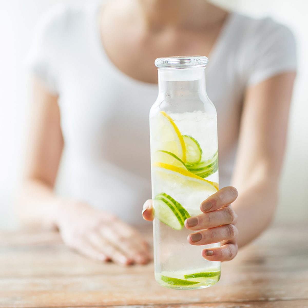 healthy eating, drinks, diet, detox and people concept - close up of woman with fruit water in glass bottle