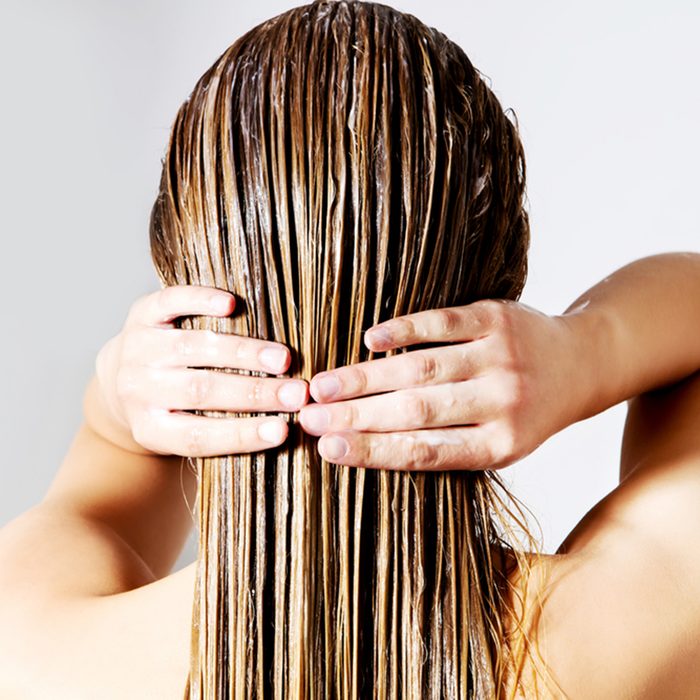 Woman applying hair conditioner. Isolated on white.