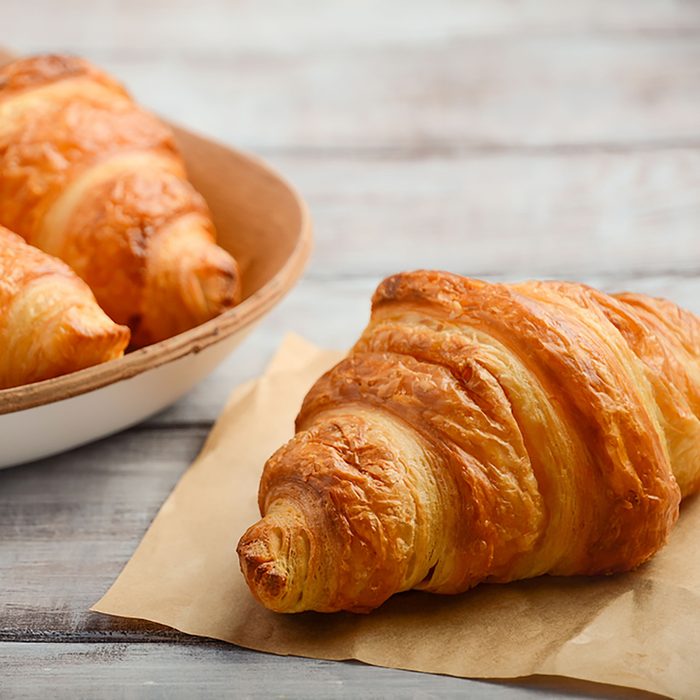 Fresh Croissants on rustic wooden background.