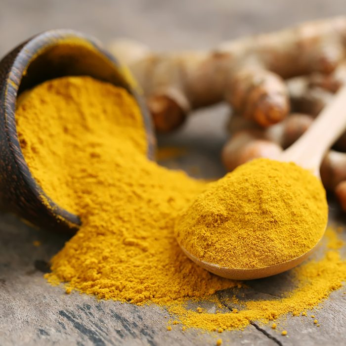 Turmeric powder and fresh turmeric on wooden background.