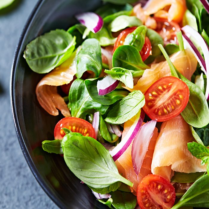 Salmon Salad with spinach, cherry tomatoes, corn salad, baby spinach, fresh mint and basil. Home made food. Concept for a tasty and healthy meal.