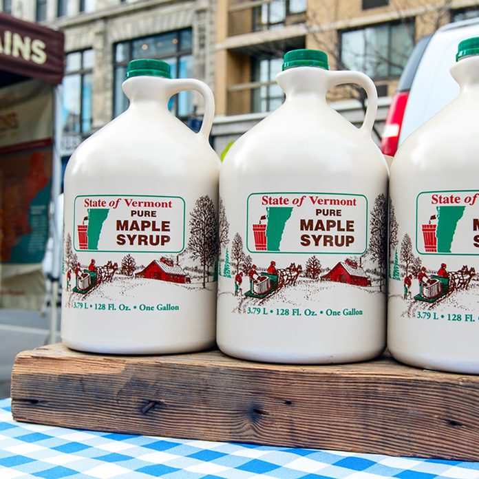 Jugs of Vermont maple syrup stand for sale at a farmer's market on Union Square
