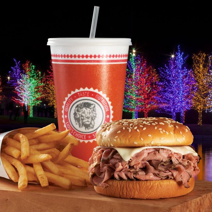 Lion's Choice sandwich, fries and soda in front of lit up trees