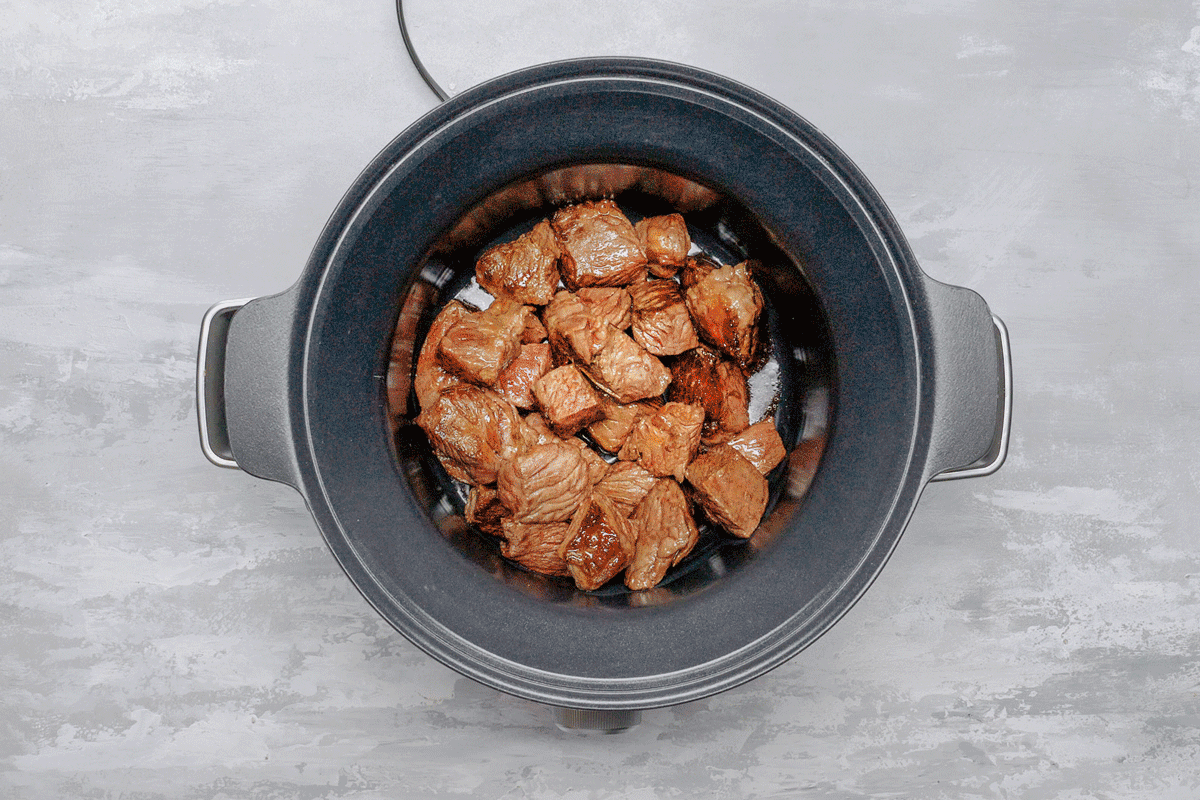 Beef pieces and vegetables in a slow cooker
