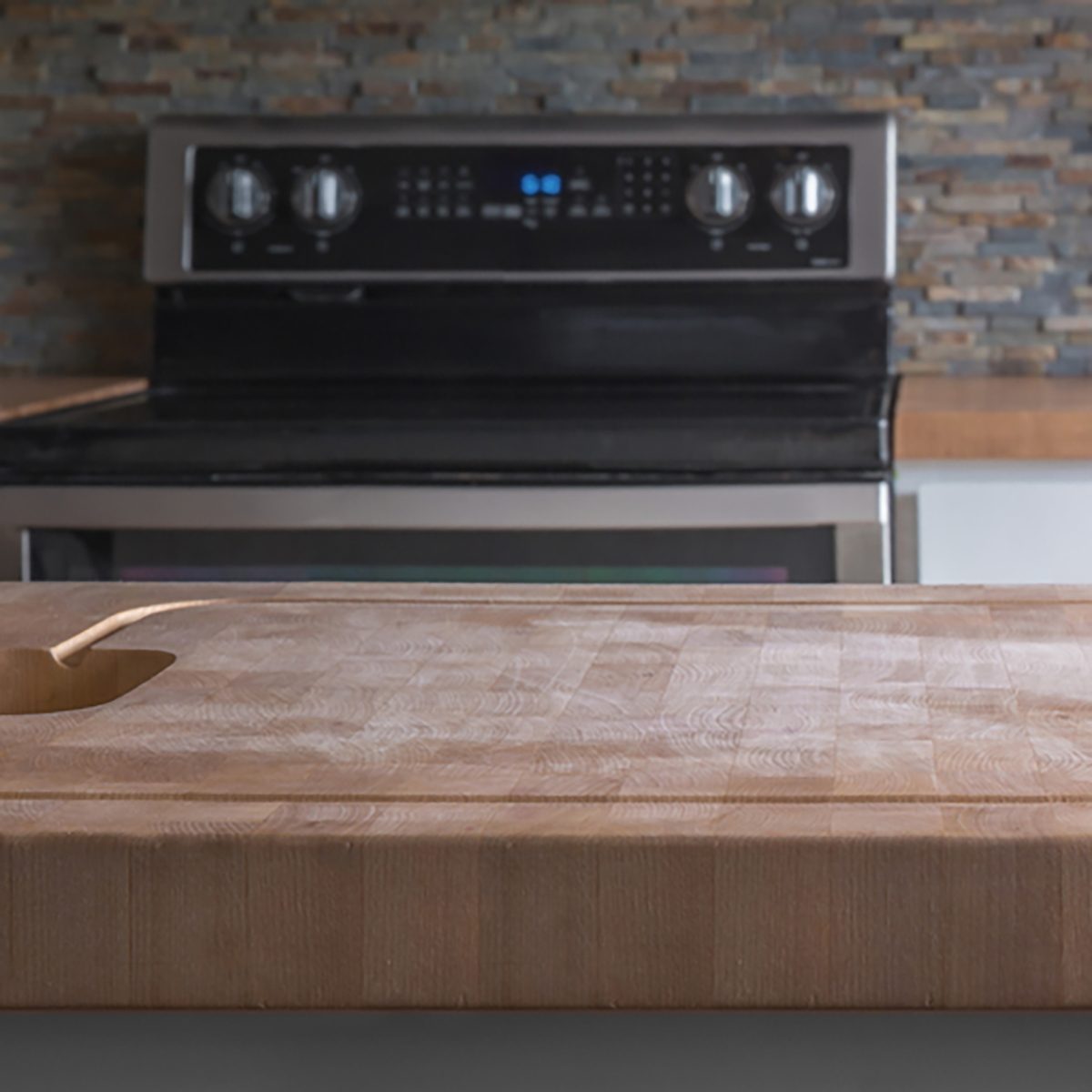 Kitchen Island wood butcher block top with stove, sink and counter in background