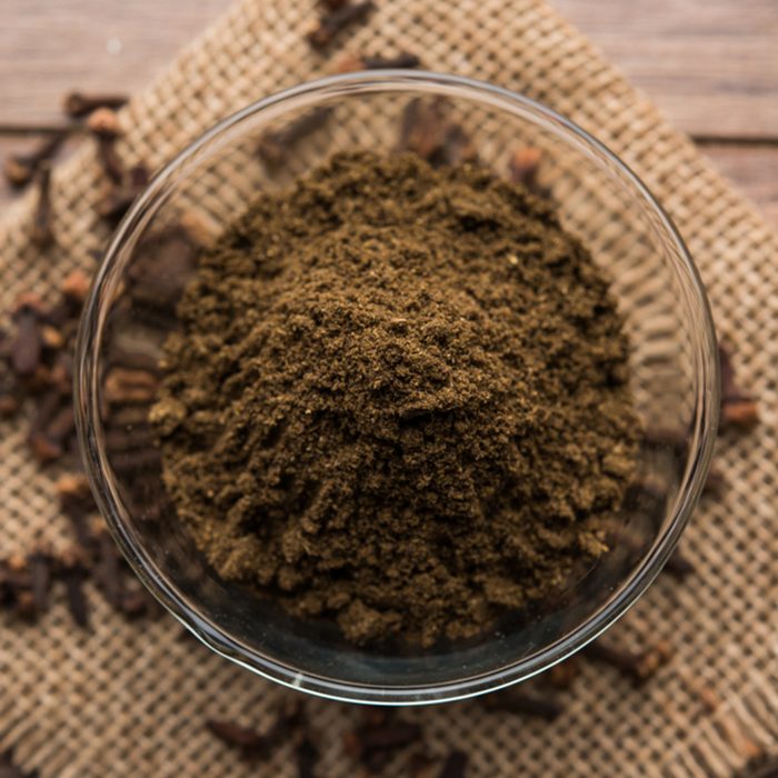 whole Cloves or laung or lavang with powder in a bowl isolated on white.