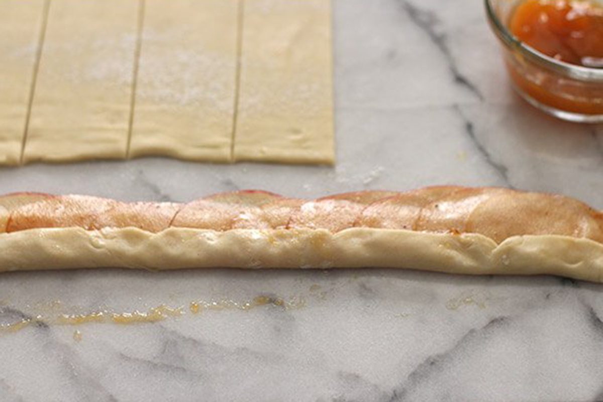 Folding dough over apple slices