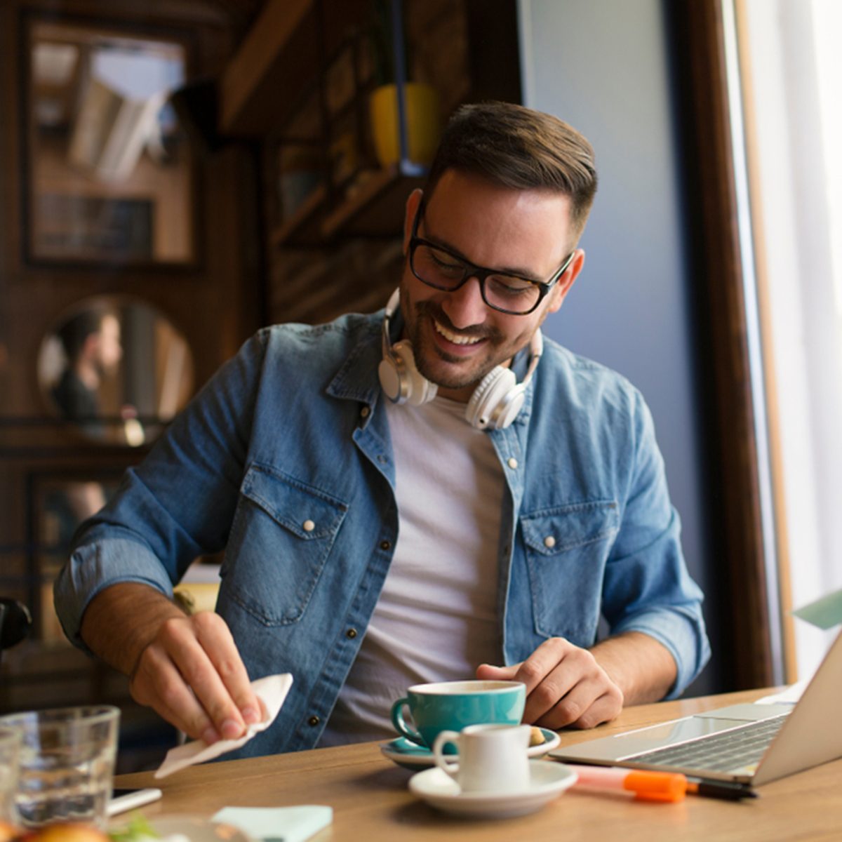Smiling young man cleaning his table at coffee shop