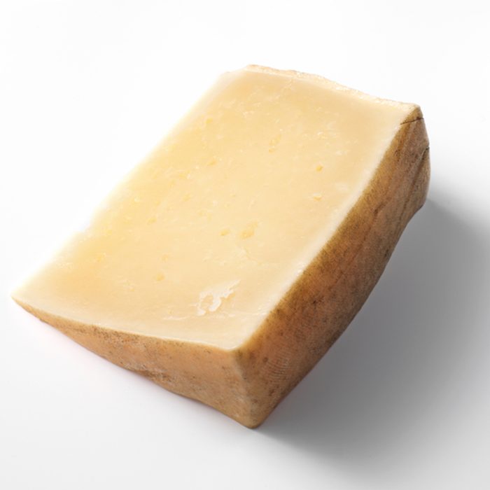 A wedge of hard Spanish Roncal, sheep's cheese, with contact shadow, isolated on white background