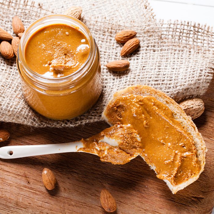 Homemade almond butter in jar on cutting board.