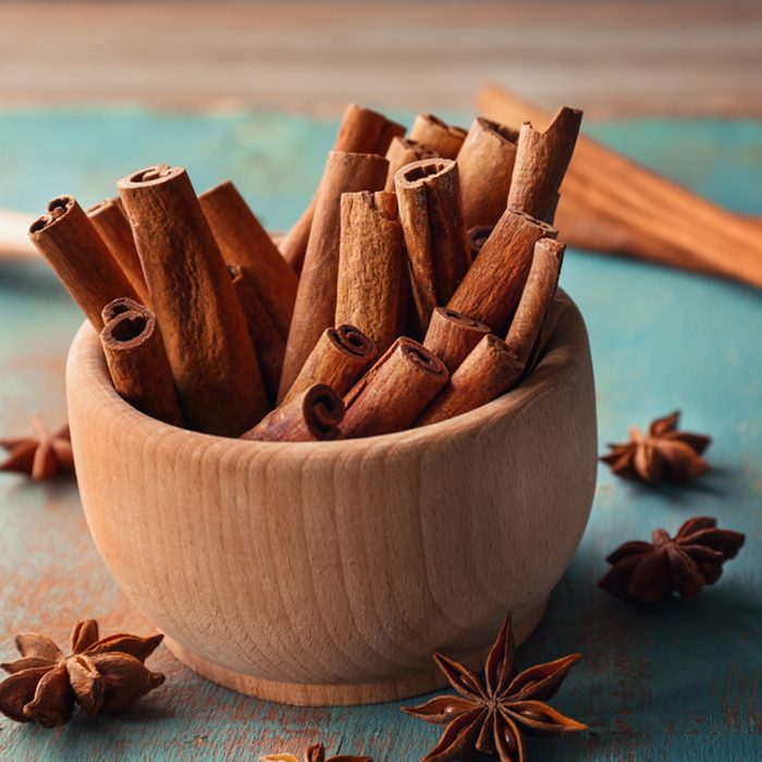 Wooden bowl with cinnamon sticks and anise on table