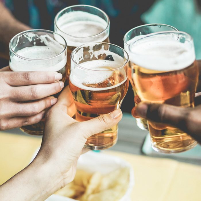 Group of friends enjoying a beer in brewery pub - Young people hands cheering at bar restaurant