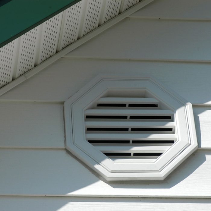 Close up of white exterior home detail of white vinyl siding and white vent with white soffit and dark green fascia, and a hint of blue sky on a sunny day.; Shutterstock ID 1182808474; Job (TFH, TOH, RD, BNB, CWM, CM): Taste of Home