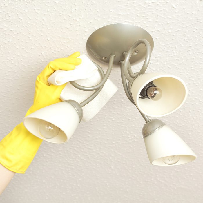ceiling light fittings with a woman's hand cleaning them with a cloth; Shutterstock ID 155752688; Job (TFH, TOH, RD, BNB, CWM, CM): TOH