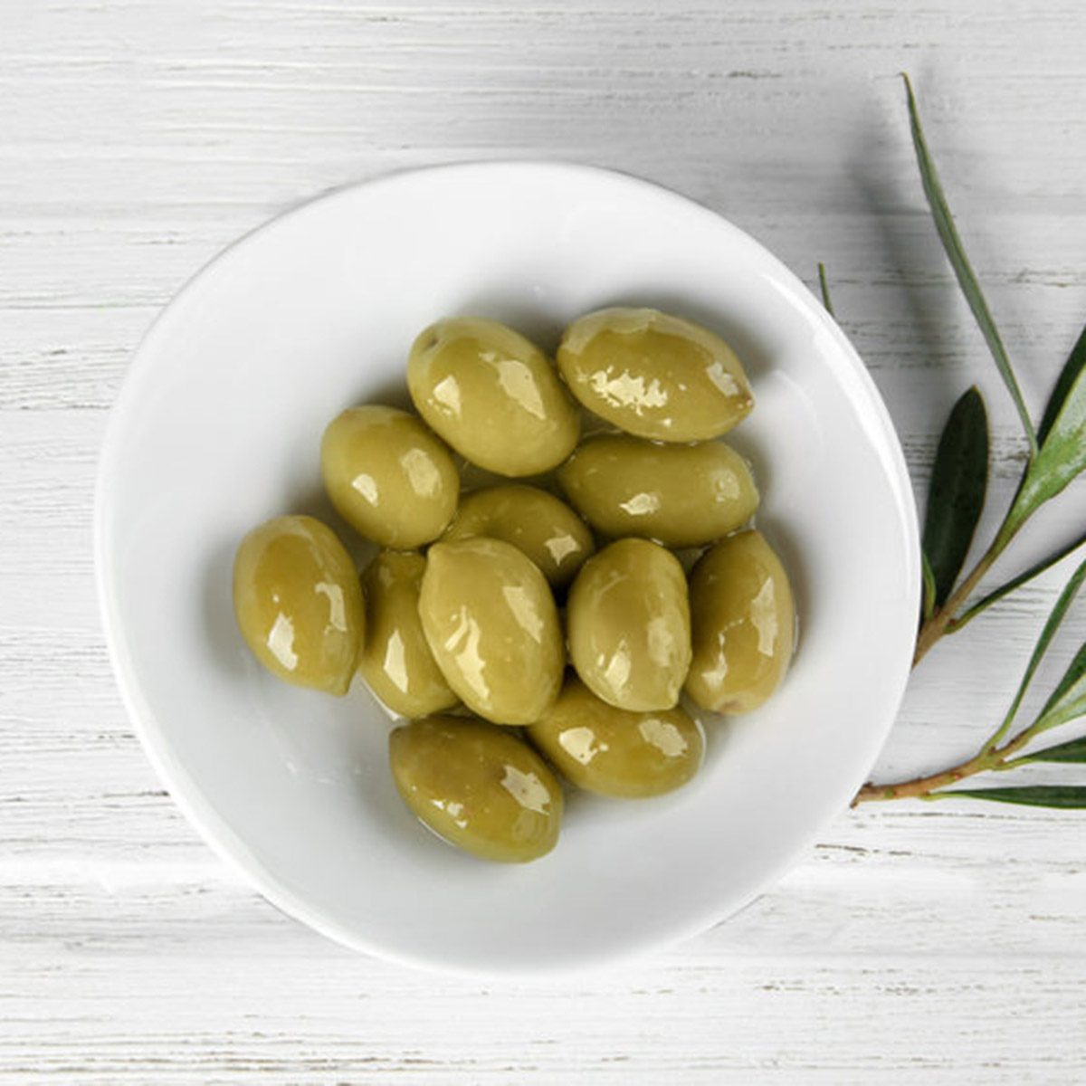 Plate with canned olives on wooden table