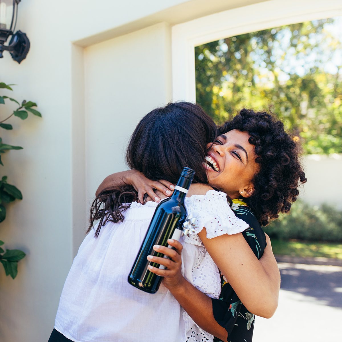 African woman greeting and embracing female friend for having a new house.