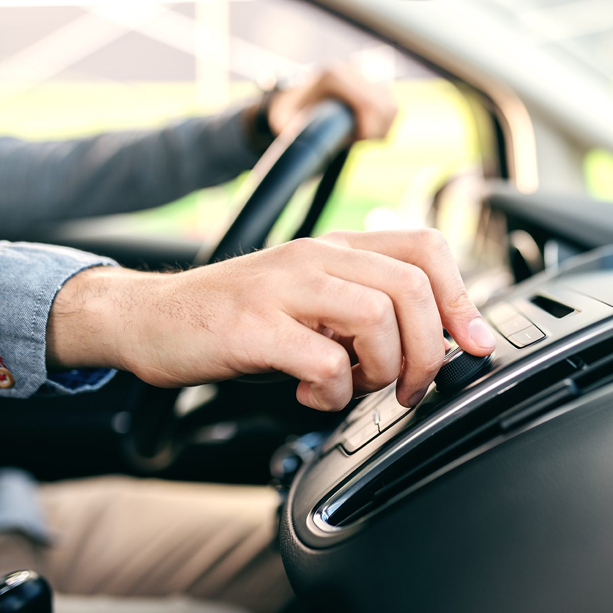 Close up of man changing radio station while driving car.