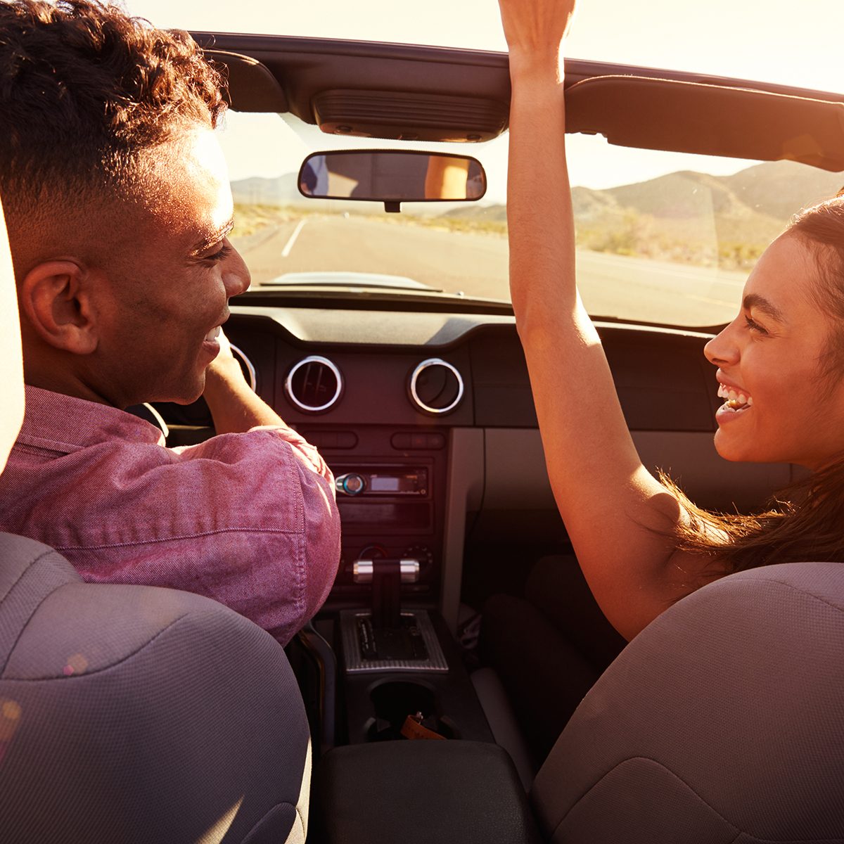 Couple On Road Trip Driving In Convertible Car