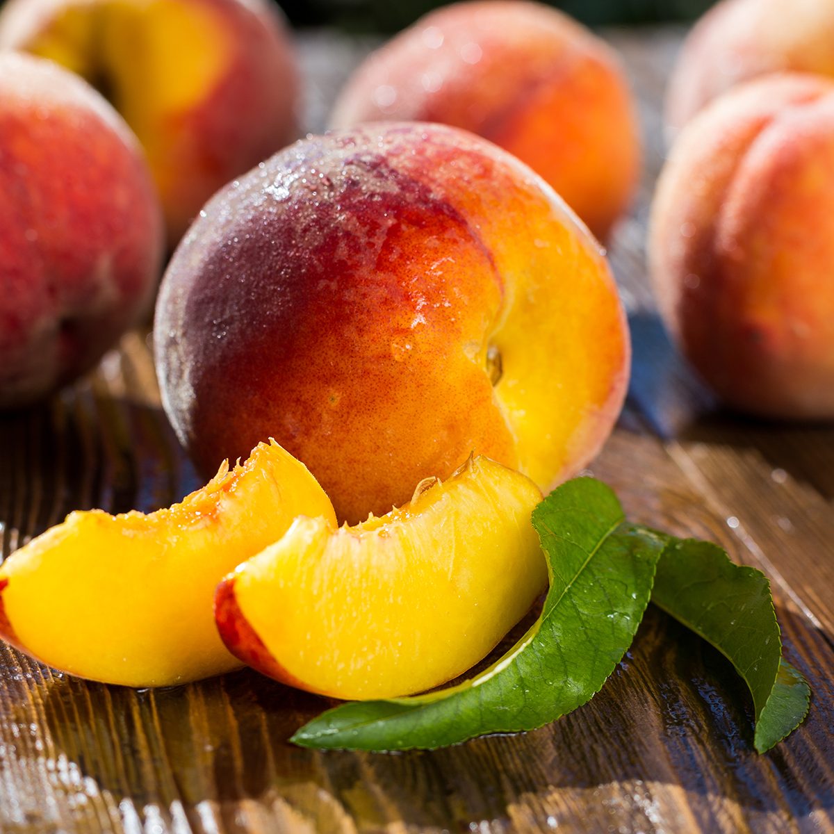 Fresh sweet group of sliced peaches on wooden background in the garden
