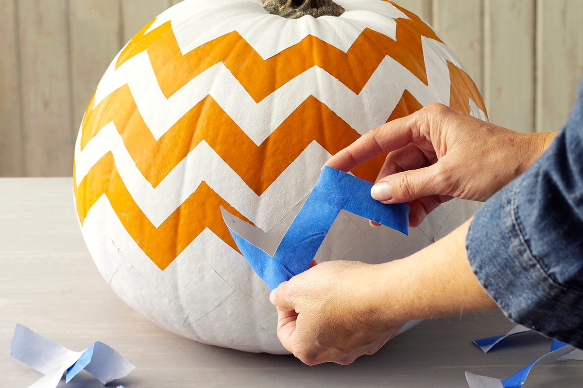 white painted pumpkin with orange zig zag lines