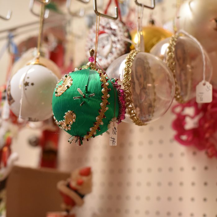 Colorful antique vintage Christmas ornaments displayed for sale on a pegboard in a thrift store.