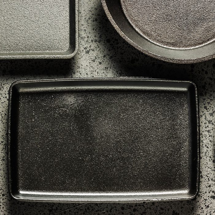 Various cast iron skillets and pans on dark background.