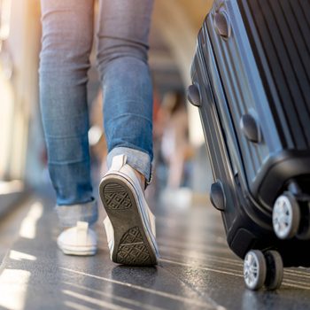 Woman traveler walking alone with suitcase bag. Travel weekend vacation trip.