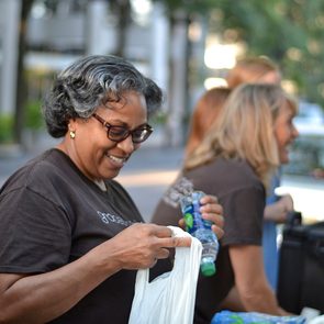 Woman putting water bottle in plastic bag while smiling