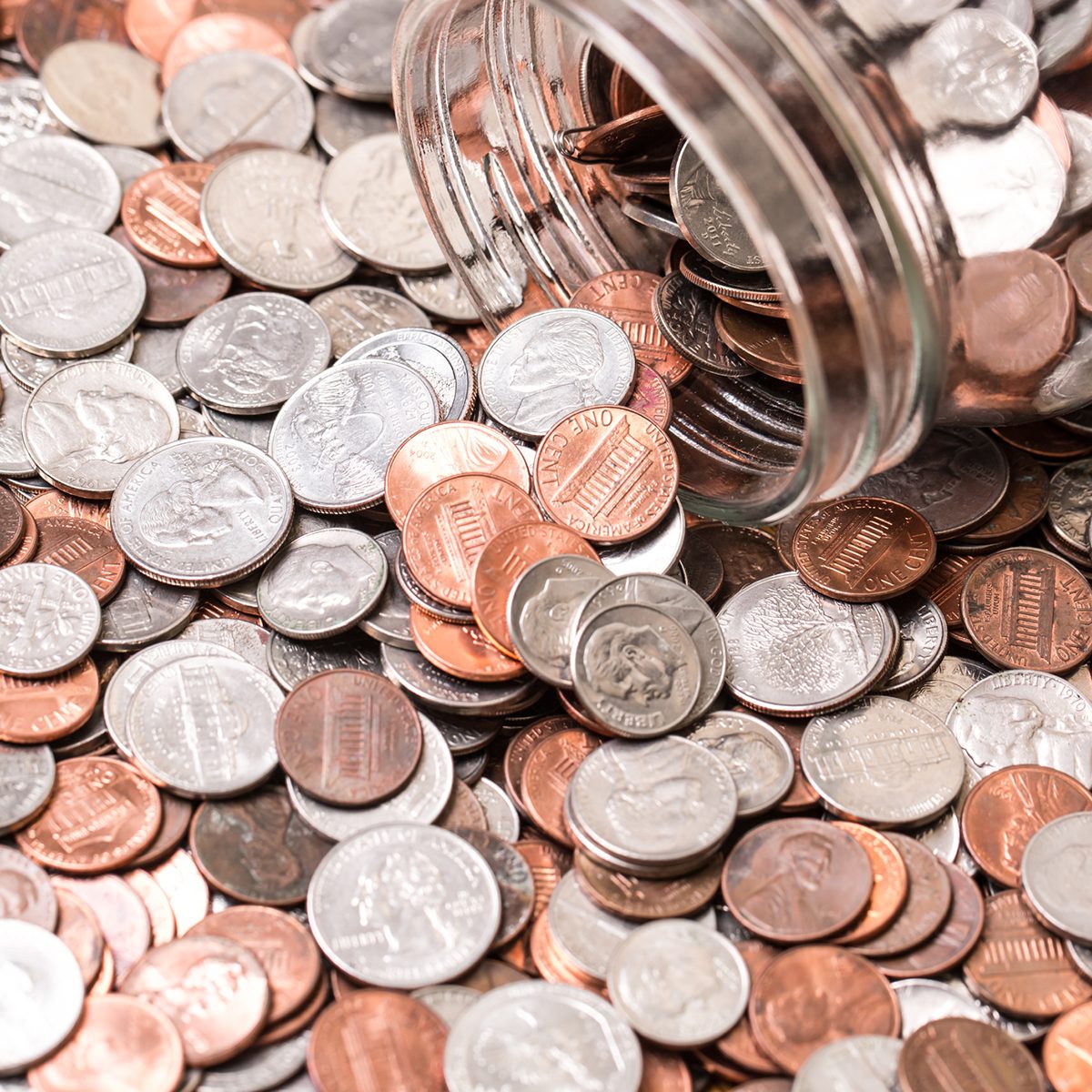 Close up of many different type of coins with jar